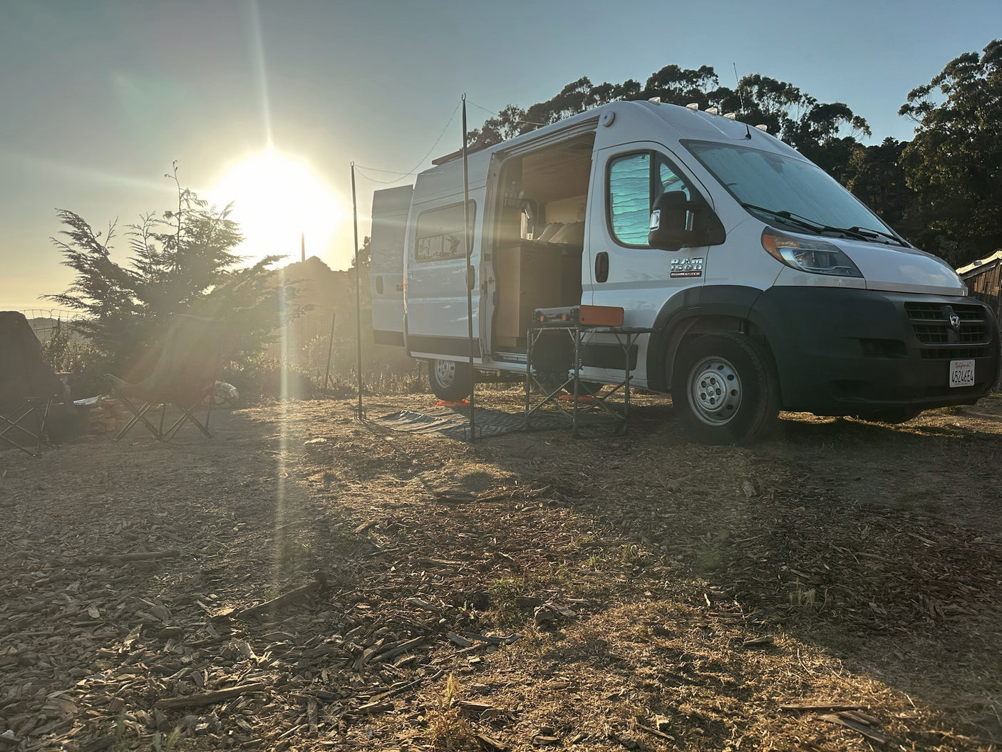 A white camper van, ideal for RV rental, parked for a peaceful sunset camp.