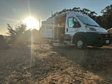 A white camper van, ideal for RV rental, parked for a peaceful sunset camp.