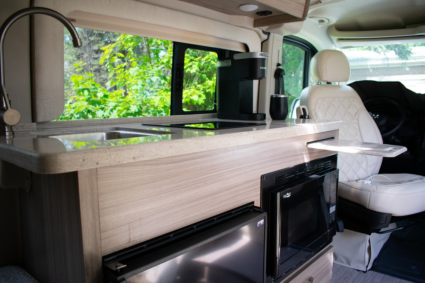  is perfectly parked by a scenic lake.|Inside an RV rental: dashboard view with a large screen showing the backup camera of a lakeside parking lot.|RV rental kitchen area features a sink — photo 3