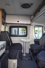 Inside this RV rental: quilted seats, a versatile table, overhead storage, and a ceiling fan offer comfort for your travels.