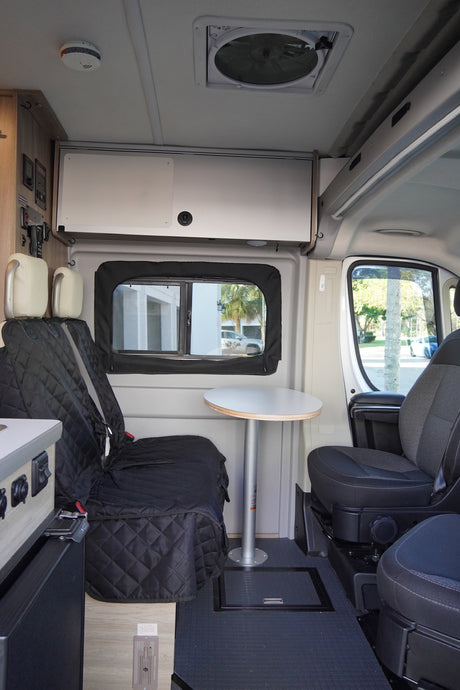 Inside this RV rental: quilted seats, a versatile table, overhead storage, and a ceiling fan offer comfort for your travels.