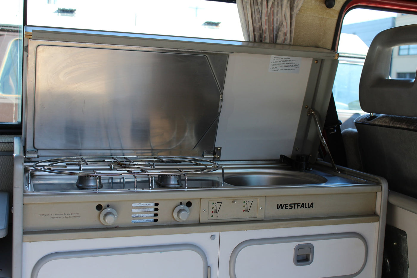 Interior view of a classic Westfalia camper van kitchen, with gas stove and sink, perfect for an RV rental. — photo 4