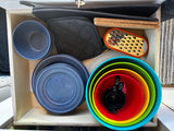 RV rental kitchen drawer: organized plates, bowls, grater, pot holders, and measuring cups for compact cooking.