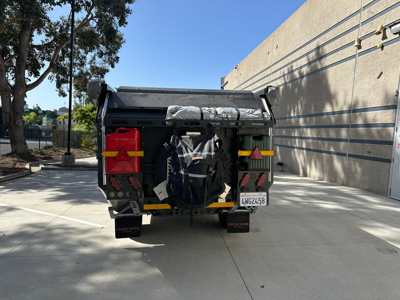 Rear view of a rugged Conqueror off-road camper trailer, packed with gear for adventure. Consider this RV rental for your next trip. — photo 7