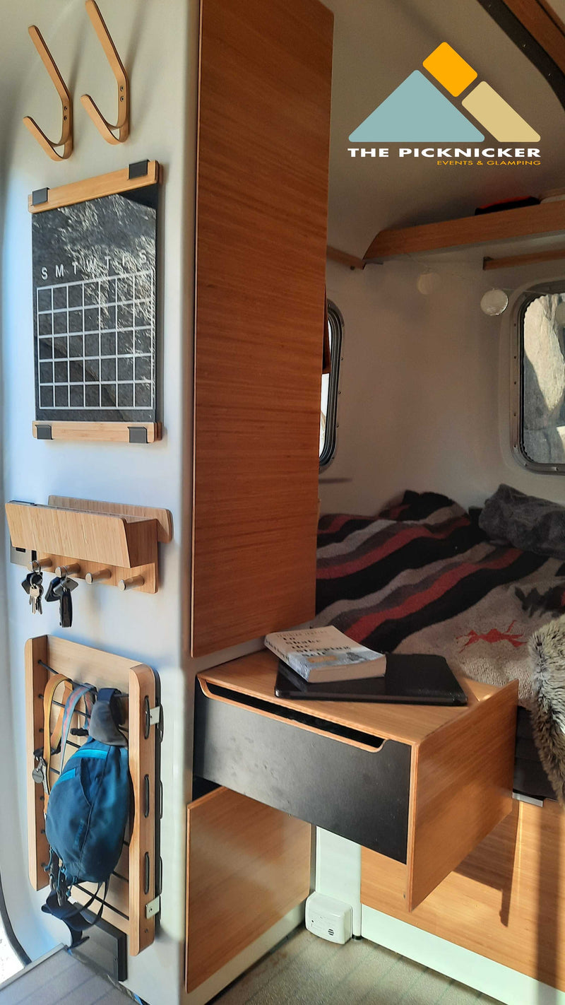 Cozy RV rental interior with practical wall storage: hooks, calendar, key holder, and bedside table. — photo 5