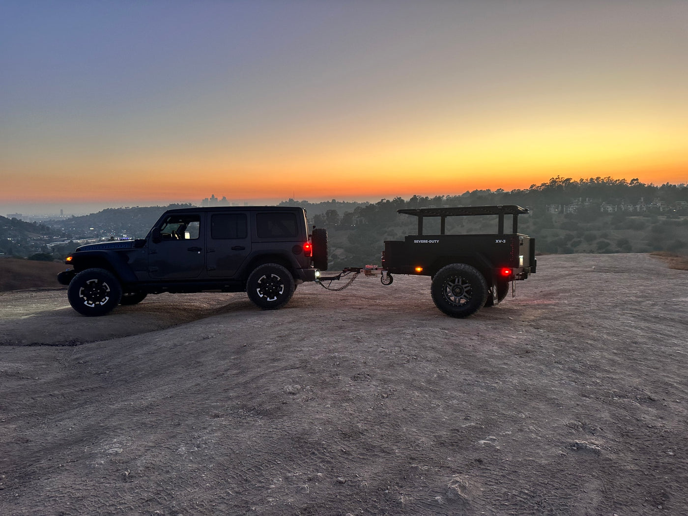 Off-road adventure ready: Dark Jeep & XV-3 trailer at sunset on a hilltop. Perfect for an RV rental getaway with stunning city views. — photo 9