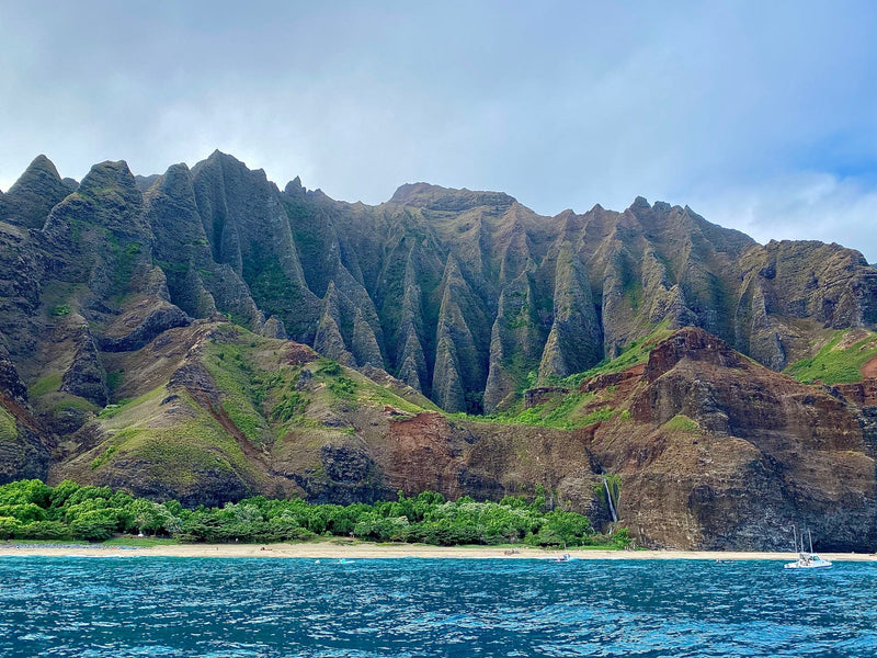 Na Pali Coast, Hawaii: towering green cliffs, beach, waterfall, blue ocean. An RV rental could explore similar wonders elsewhere. — photo 11