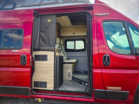 This red camper van RV rental, with its side door open, showcases a functional interior, ready for your next road trip adventure.