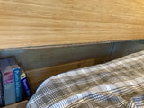 Inside this cozy **rv rental**, discover nature books next to a comfy plaid bed. Ideal storage for your next adventure.