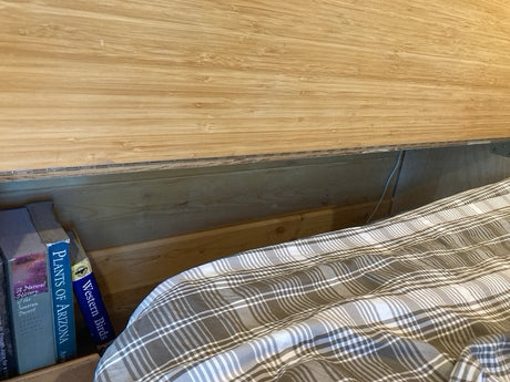 Inside this cozy **rv rental**, discover nature books next to a comfy plaid bed. Ideal storage for your next adventure.