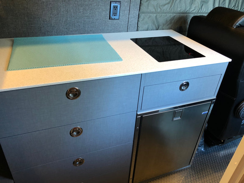 Inside an RV rental: a compact kitchen with induction cooktop, built-in fridge, and textured blue counter mat. — photo 7