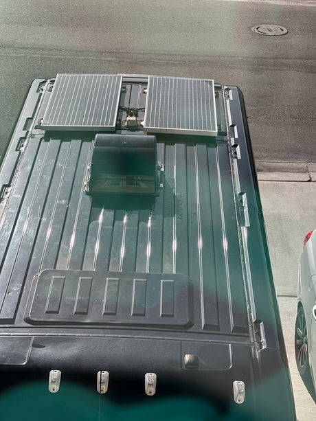 An rv rental campervan's roof, showcasing solar panels, a vent, and lights for power and ventilation on trips.