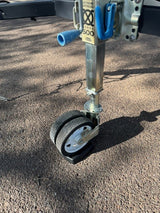 Close-up of a trailer jack with dual wheels, ideal for an RV rental. Provides mobility and stability for your caravan.