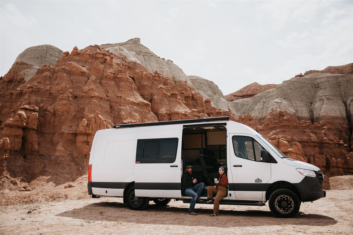 Two people relax in a white **RV rental** camper van