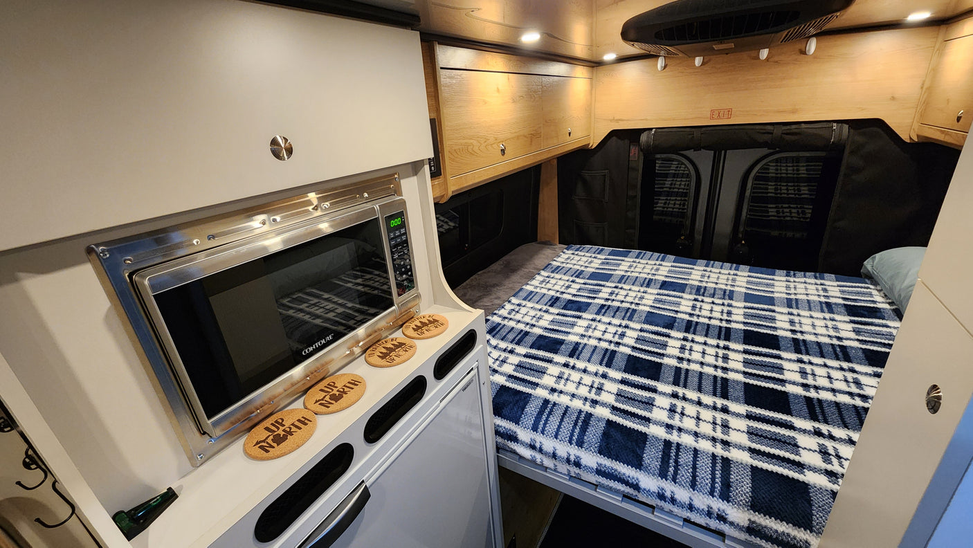 Step inside this cozy RV rental, featuring a microwave, comfortable bed, and ample storage cabinets for your next adventure.