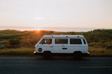White camper van parked on a road at sunset. The perfect rv rental for a scenic road trip adventure.