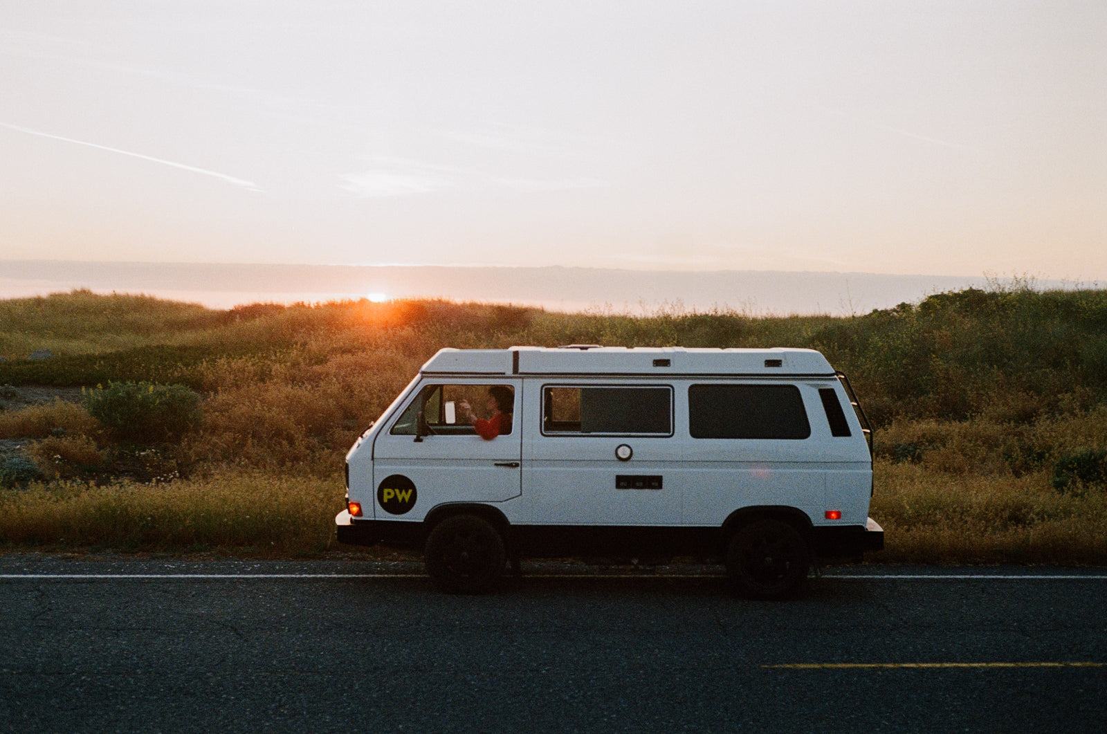 White camper van parked on a road at sunset. The perfect rv rental for a scenic road trip adventure.