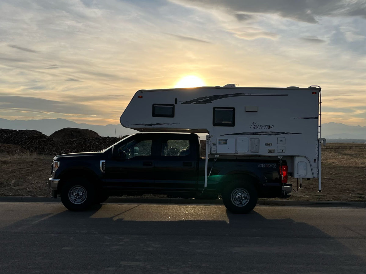  perfect for outdoor adventures and camping.|Black Ford Super Duty truck with a Northstar truck camper setup.|RV rental interior showing a snug bed with soft bedding — photo 5