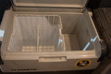 An empty Dometic portable cooler in an RV rental, featuring an open lid, wire basket, and storage area.