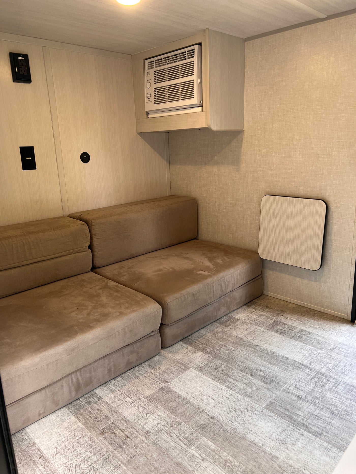This cozy RV rental features a modular sofa, AC unit, wall outlets, and a foldable table, ideal for compact mobile living. — photo 8