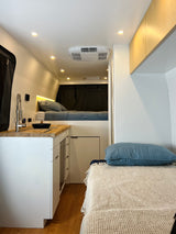 Modern RV rental interior featuring a compact kitchen, cozy beds, and bright lighting for comfortable travels.