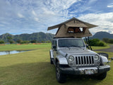 Silver Jeep with rooftop tent on Kauai's scenic golf course. An RV rental alternative for mountain adventures.