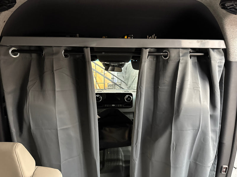 RV rental interior view: gray privacy curtains on a rod, separating the front cabin from the living area, with overhead storage. — photo 9