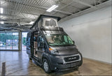 Gray Ram ProMaster camper van RV rental with pop-top roof, showcasing its interior from a service bay.