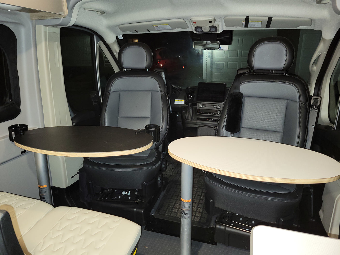 RV rental interior: swivel seats and dining tables set up for a cozy meal inside a modern camper van.