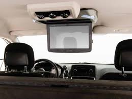 RV rental interior: A ceiling-mounted, flip-down entertainment screen and controls, viewed from the rear passenger seats.