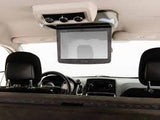 RV rental interior: A ceiling-mounted, flip-down entertainment screen and controls, viewed from the rear passenger seats.