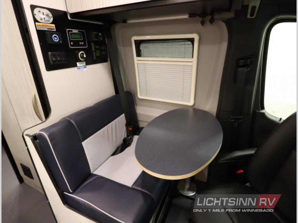 Explore this RV rental's cozy interior: a dinette with a blue/white bench, oval table, and user-friendly control panel.