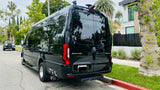 Black Mercedes Sprinter 3500XD RV rental, with roof equipment, parked on a sunlit residential street.
