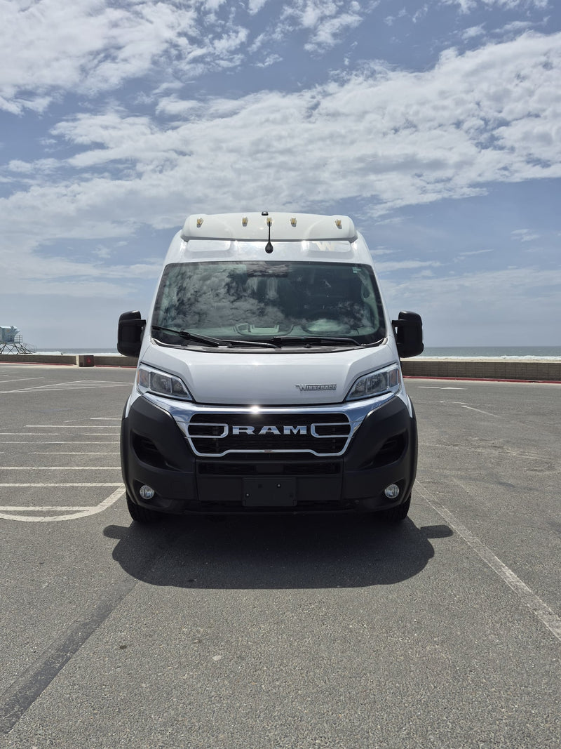  ready for adventure.|A white Winnebago Ram Promaster camper van (rv rental) parked by the ocean on a cloudy day.|This white RAM camper van — photo 2