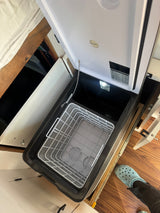 Open portable BougeRV fridge/freezer inside an RV rental, featuring its basket, light, and compact design.