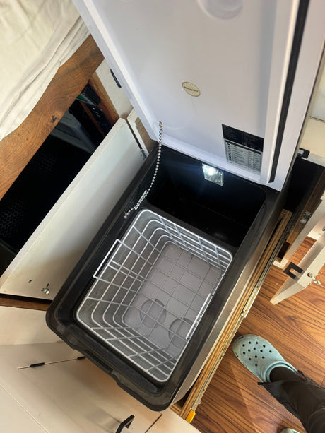 Open portable BougeRV fridge/freezer inside an RV rental, featuring its basket, light, and compact design.