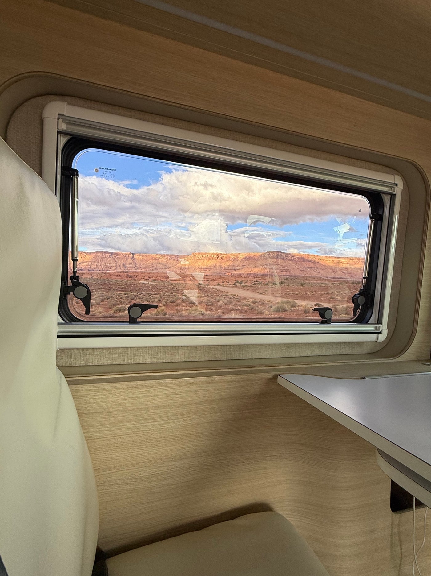Scenic desert view from an RV rental window, showing comfortable interior seating and a table. — photo 11
