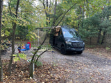 This rv rental is set up at a forest campsite (site 508) with chairs, fire pit, and autumn leaves.