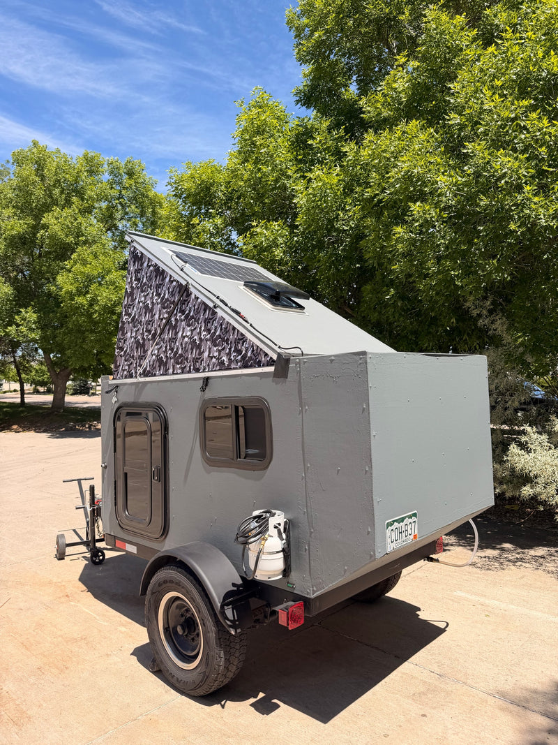 A gray pop-top camper trailer with solar panels and a propane tank, ideal for your next RV rental adventure. — photo 2
