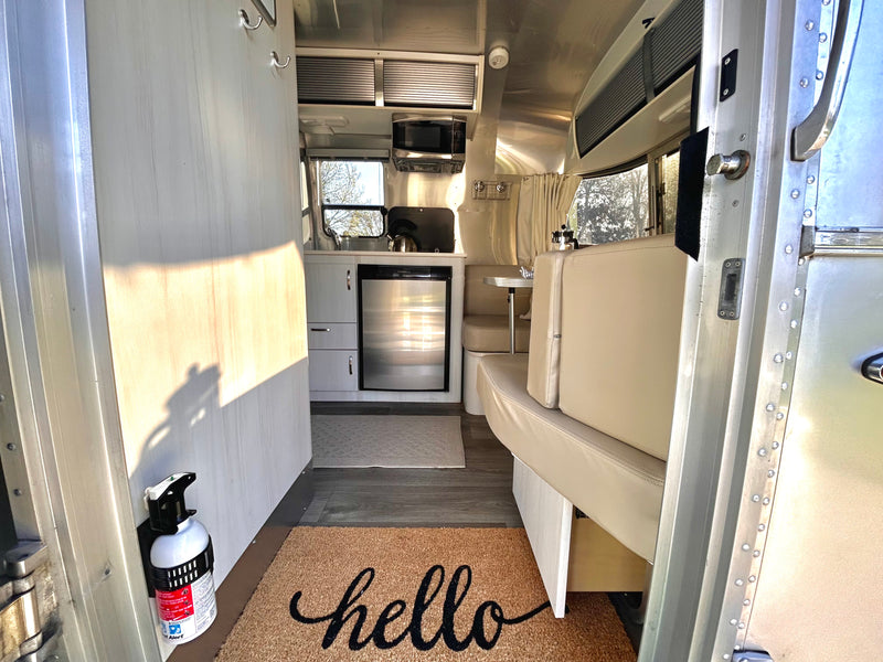 Cozy Airstream RV rental interior with kitchen, dining, and "hello" mat. Bright and modern. — photo 4