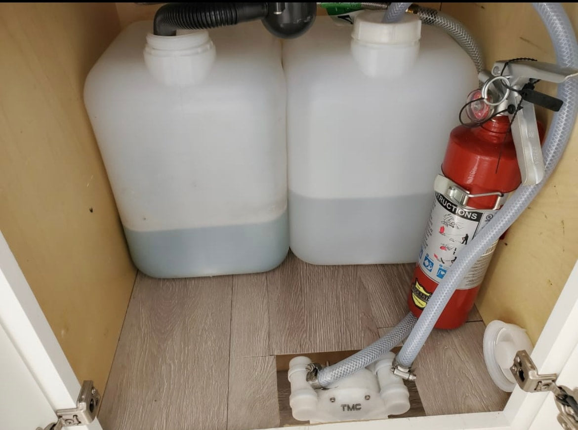 RV rental: Under-sink setup with partially filled portable water tanks, water pump, and fire extinguisher. — photo 15