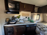 This RV rental boasts a functional kitchen with a microwave, stovetop, sink, and a comfortable sleeping area.