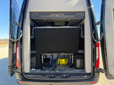 Rear view of an RV rental camper van with open doors, showcasing its versatile interior bed and storage area.