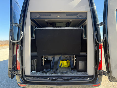 Rear view of an RV rental camper van with open doors, showcasing its versatile interior bed and storage area.