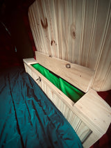 RV rental space: Custom wood storage with bright green lining & open lid, beside a dark sleeping bag. Ideal for campervan living.