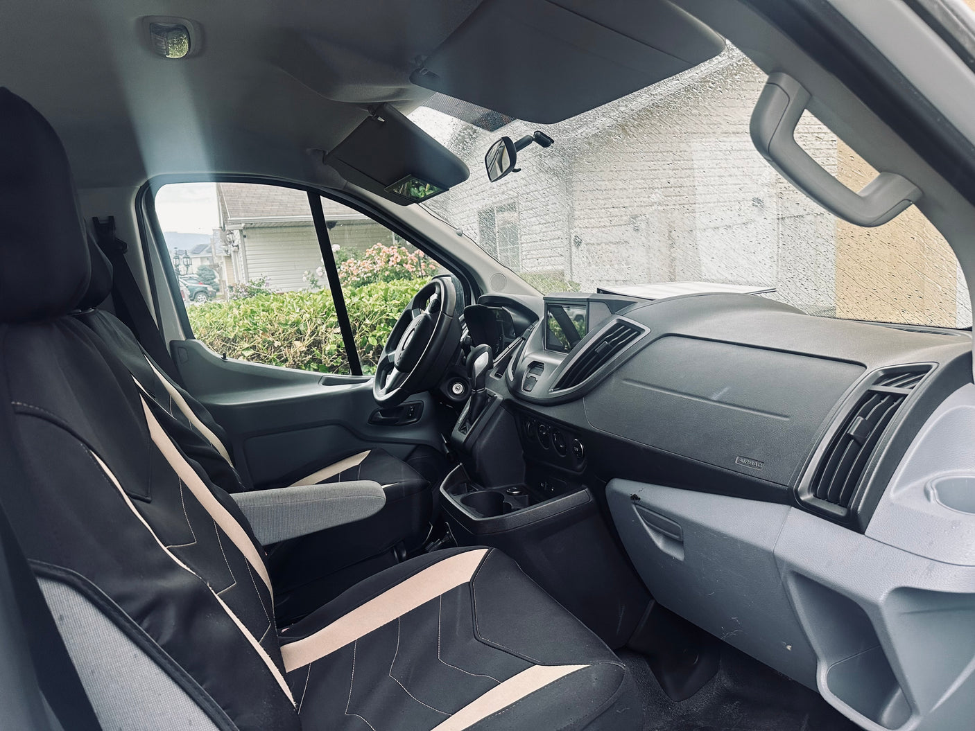 Experience comfort in this van's interior, ideal for your RV rental journey. Features driver's area, dash, and rainy windshield.