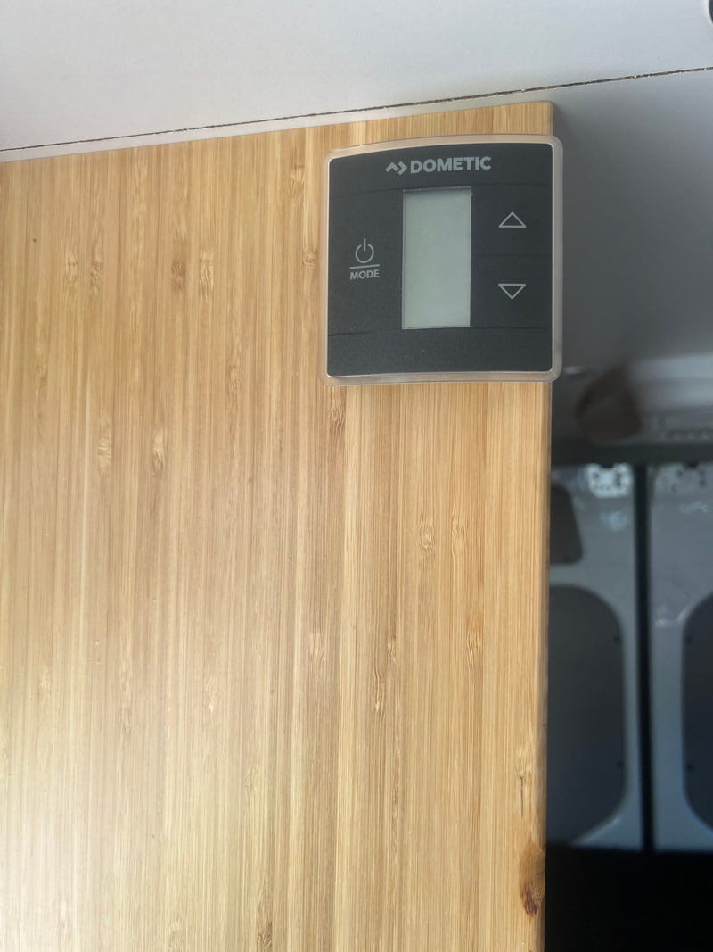 Dometic control panel on light bamboo wall inside an RV rental, showing power/mode & adjustment buttons for climate. — photo 14
