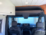 Inside an RV rental: Looking forward from the custom living space to the driver's cabin with overhead storage.