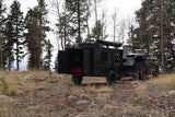 Overland trailer (RV rental) and SUV parked amidst pine and aspen trees, with mountains in the background, ready for adventure.