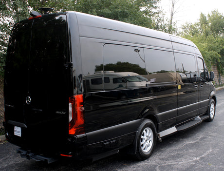 Black Mercedes-Benz Sprinter van, seen from rear-right, suitable for luxury RV rental or executive travel. Reflections show other RVs.